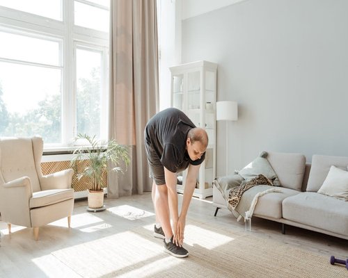 man doing light morning stretches near window in a bright room